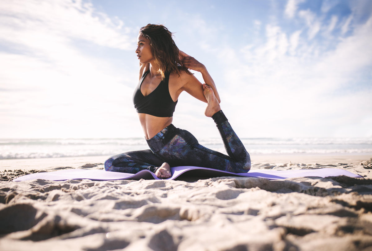 Duschrückwand-Junges Mädchen in King Pigeon Yoga Pose am Strand