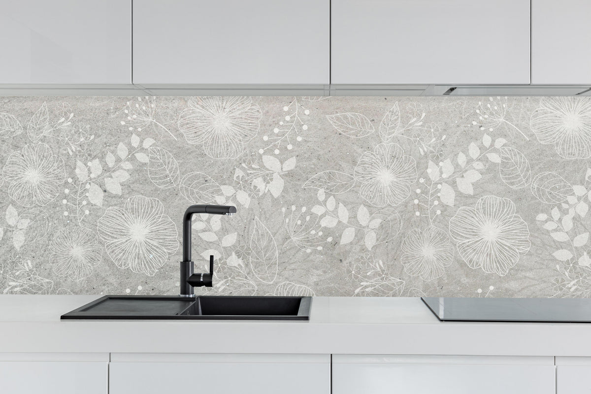 Küche - Blumen auf grauem Beton hinter weißen Hochglanz-Küchenregalen und schwarzem Wasserhahn