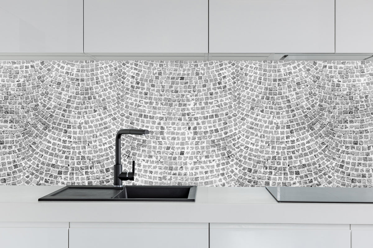 Küche - Gepflasterte Straßenoberfläche hinter weißen Hochglanz-Küchenregalen und schwarzem Wasserhahn