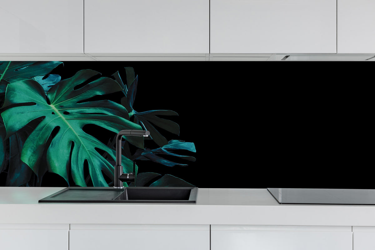 Küche - Monstera deliciosa - tropische Blätter hinter weißen Hochglanz-Küchenregalen und schwarzem Wasserhahn