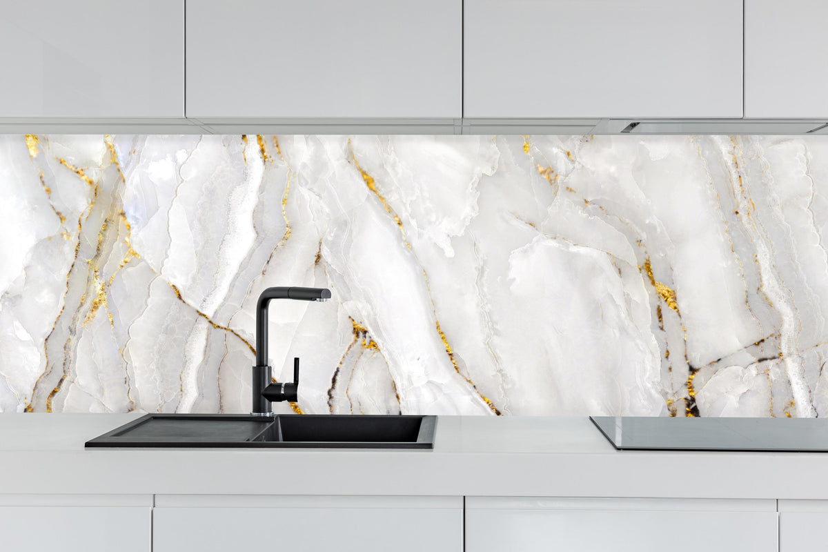 Küche - Weißer Statuario-Marmor mit goldene Adern hinter weißen Hochglanz-Küchenregalen und schwarzem Wasserhahn