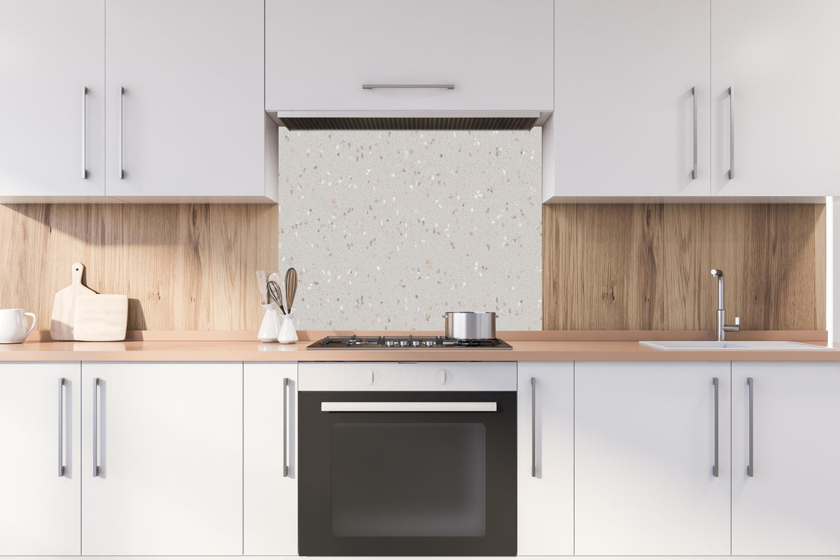 Spritzschutz - Graue Mosaiksteine hinter einem Cerankochfeld zwischen Holz-Kochutensilien