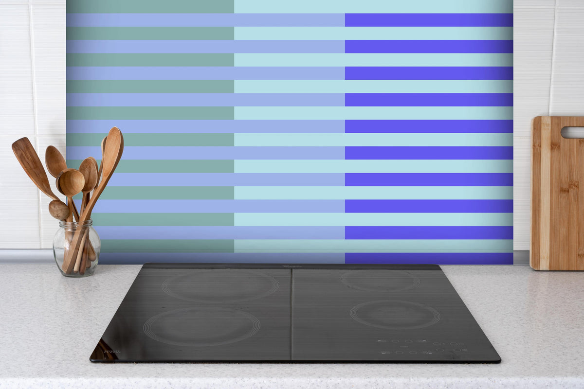 Spritzschutz - The Blues - Multy Stripes - Lavender hinter einem Cerankochfeld zwischen Holz-Kochutensilien