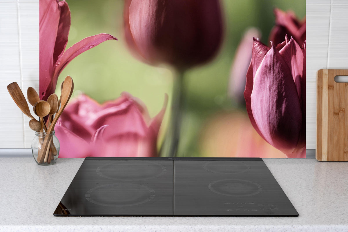 Küche - Dunkelrosa Tulpen hinter Cerankochfeld und Holz-Kochutensilien