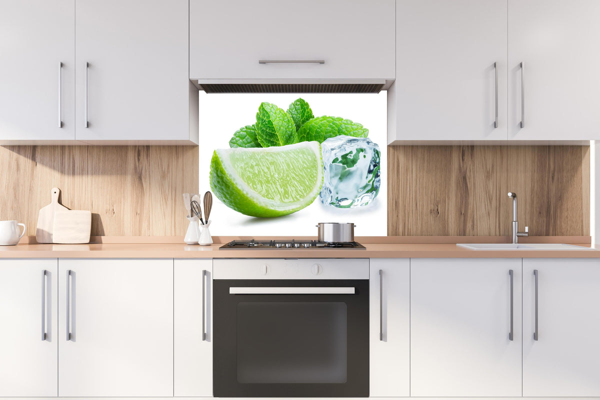 Spritzschutz - Limettenscheibe mit Eis und Minze hinter einem Cerankochfeld zwischen Holz-Kochutensilien
