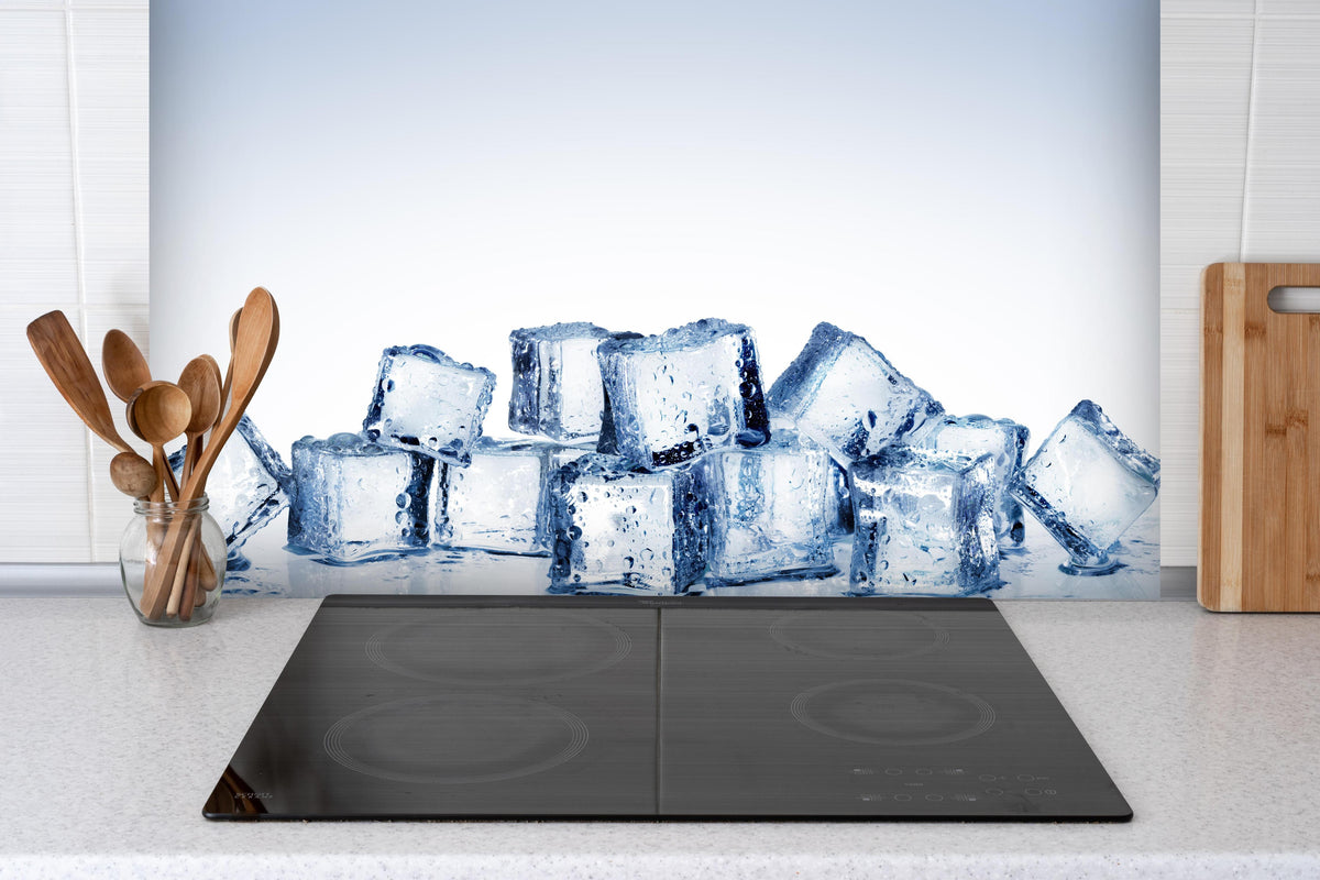 Spritzschutz - Nahaufnahme von quadratische Eiswürfel hinter einem Cerankochfeld zwischen Holz-Kochutensilien
