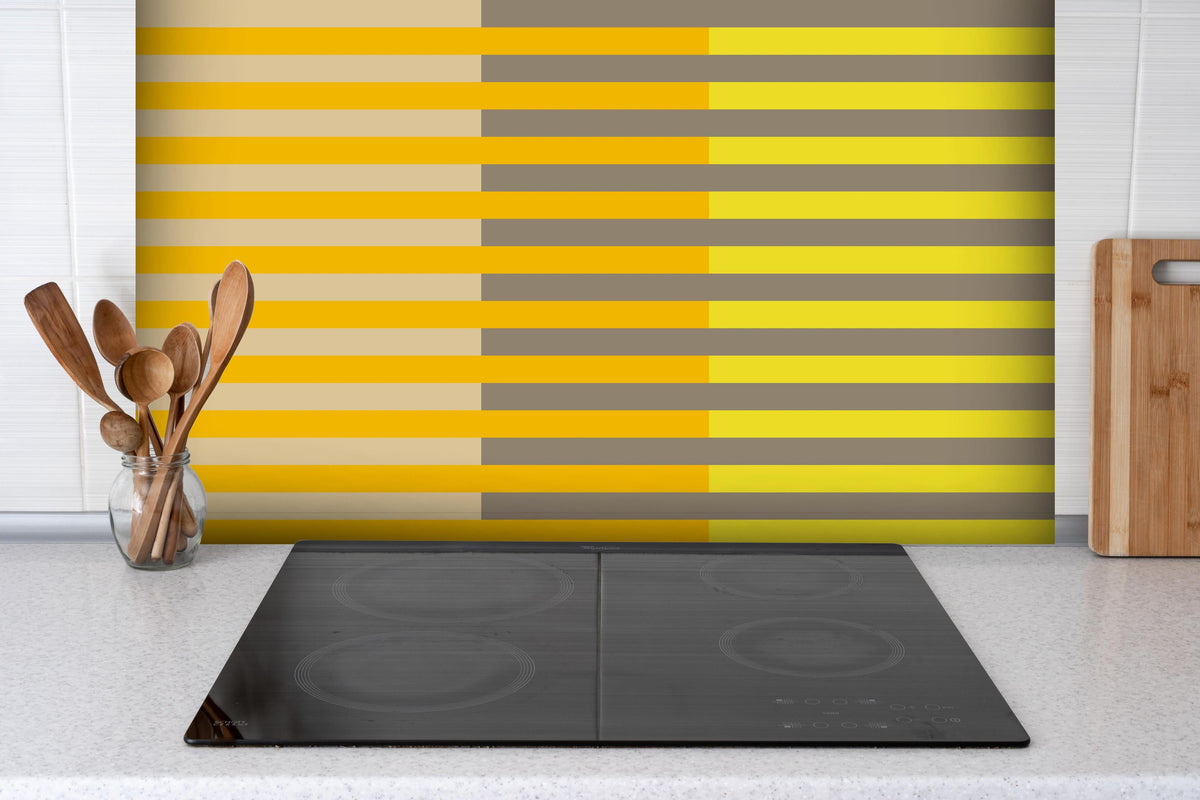 Spritzschutz - The Yellows - Multy Stripes - Honey hinter einem Cerankochfeld zwischen Holz-Kochutensilien
