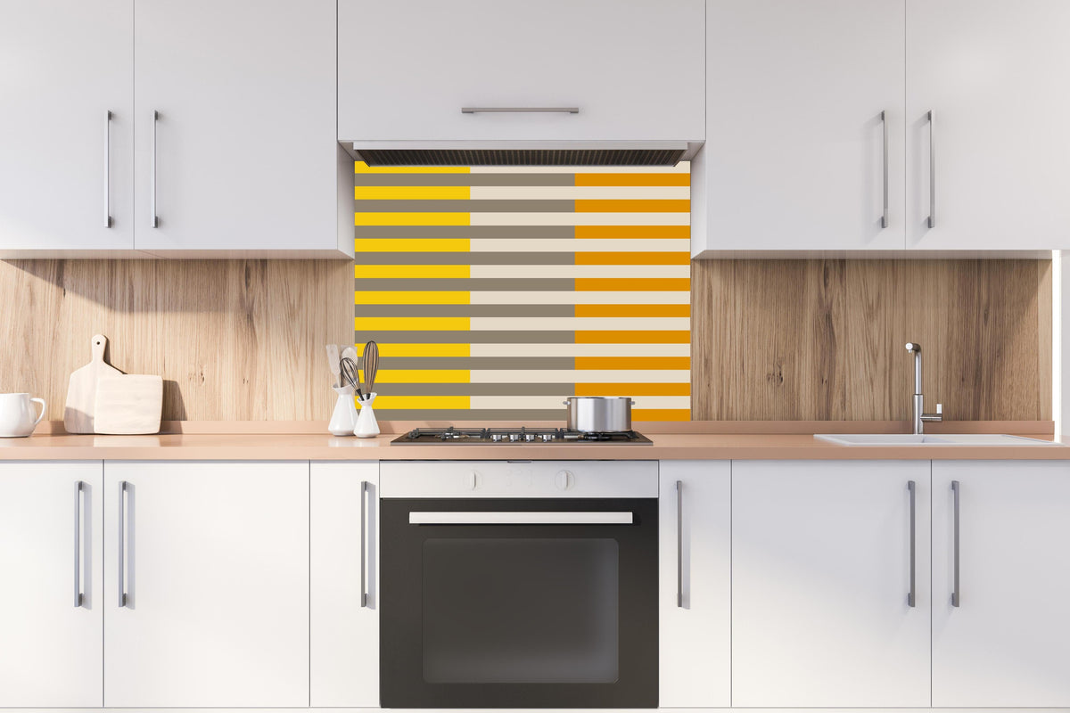 Spritzschutz - The Yellows - Multy Stripes - Saffron hinter einem Cerankochfeld zwischen Holz-Kochutensilien

